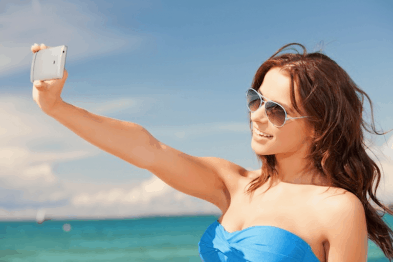 woman on the beach taking pictures with a phone