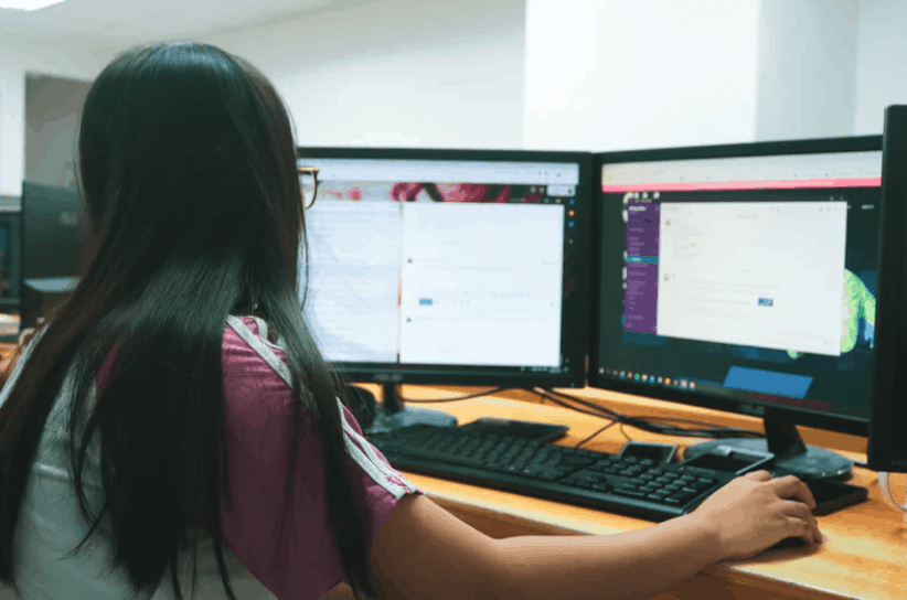 woman in front of two computer screens